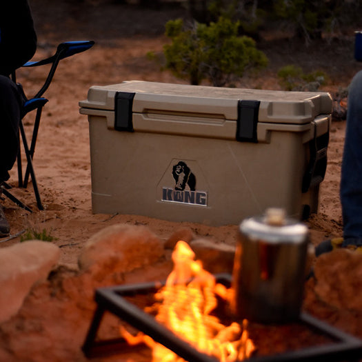 A KONG Cooler 50 quart rotomolded cooler camp beside a camp fire